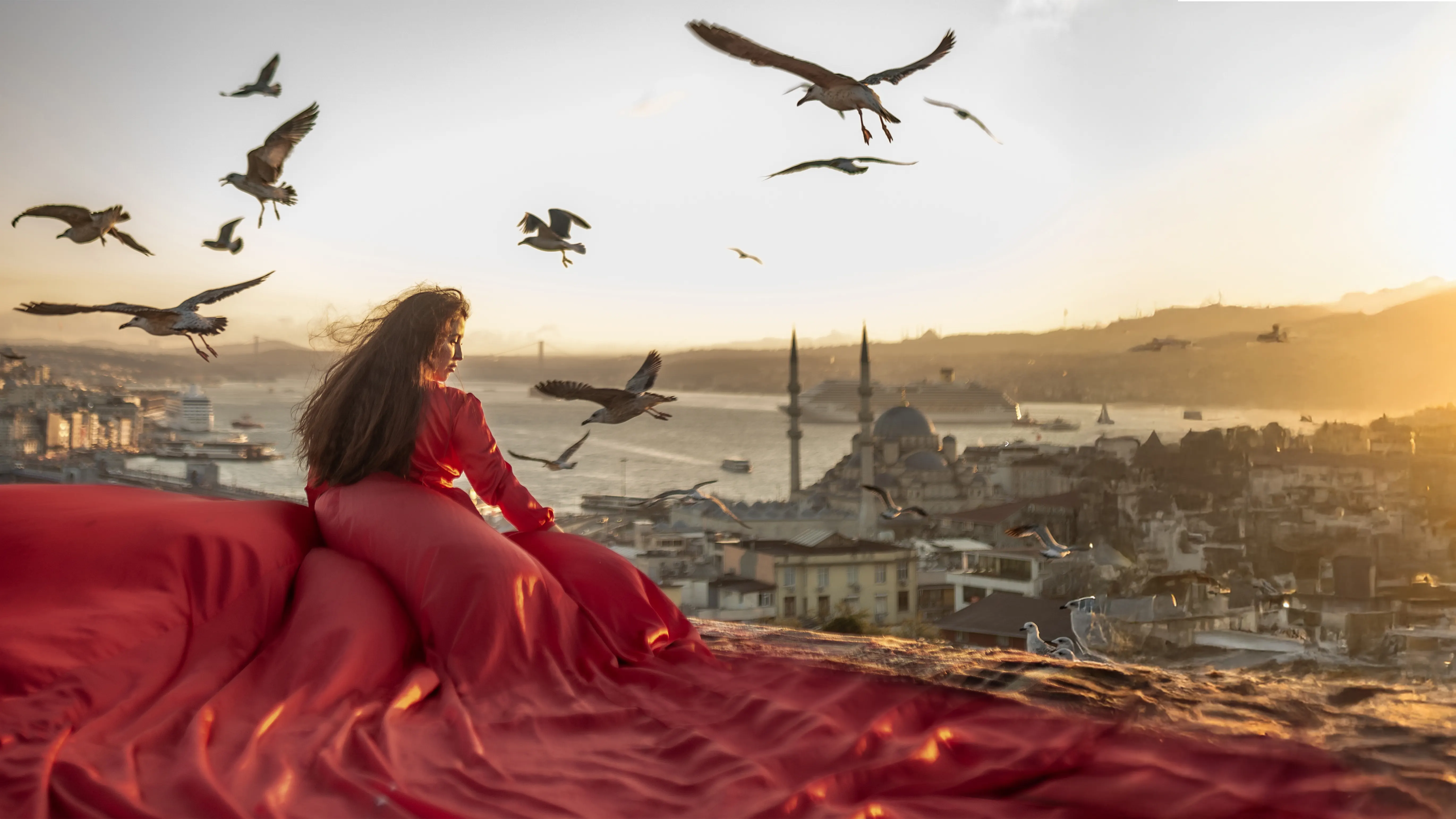 Red flying dress rooftop photoshoot in Istanbul at sunset with seagulls and Bosphorus view