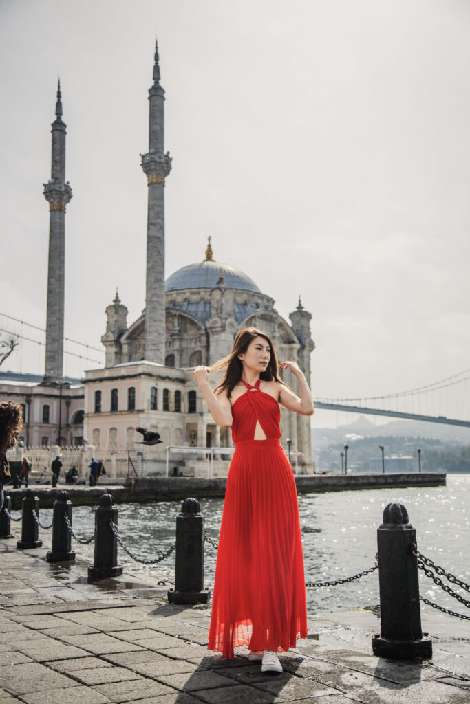 Woman wearing a red dress in front of Ortaköy Mosque on the Bosphorus waterfront