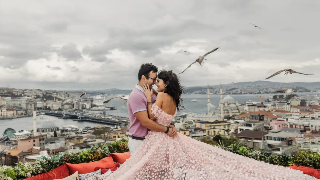 Romantic couple embracing during a rooftop photoshoot with panoramic Istanbul skyline and seagulls