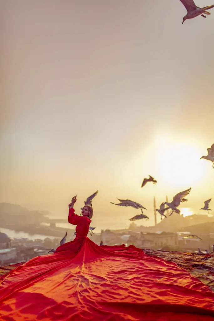 Rooftop photoshoot in Istanbul with a red flying dress at sunrise overlooking the Golden Horn