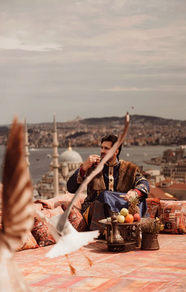 Luxury rooftop photoshoot in Istanbul featuring a man in traditional Ottoman-inspired attire with panoramic city views with flying seagulls